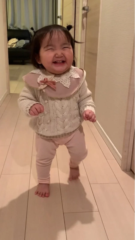 室内で満面の笑みを浮かべて歩く赤ちゃん