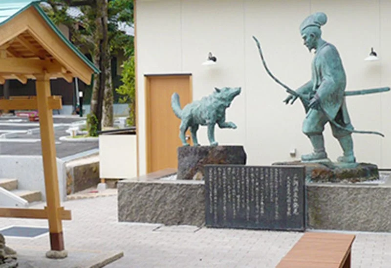 弓と刀を持つ男性と狼の銅像