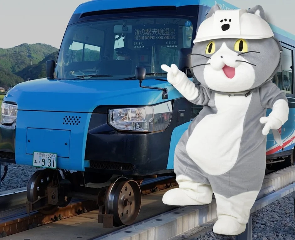 DMVと白いヘルメットをかぶった猫のマスコットが道の駅 宍喰温泉に立つ様子