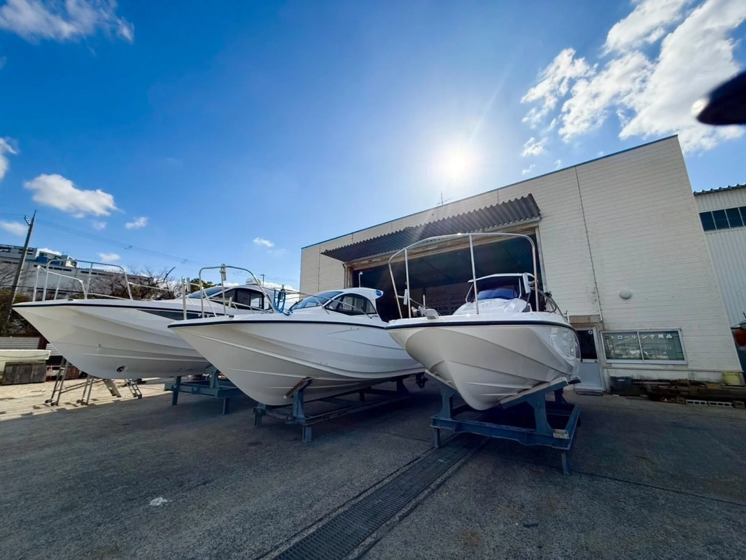 青い空の下、白いボートが複数、屋外の船台に置かれている様子。