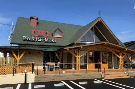 青空の下、緑色の屋根と木材のアクセントが特徴的な「PARIS MIKI」の店舗外観が写っています。