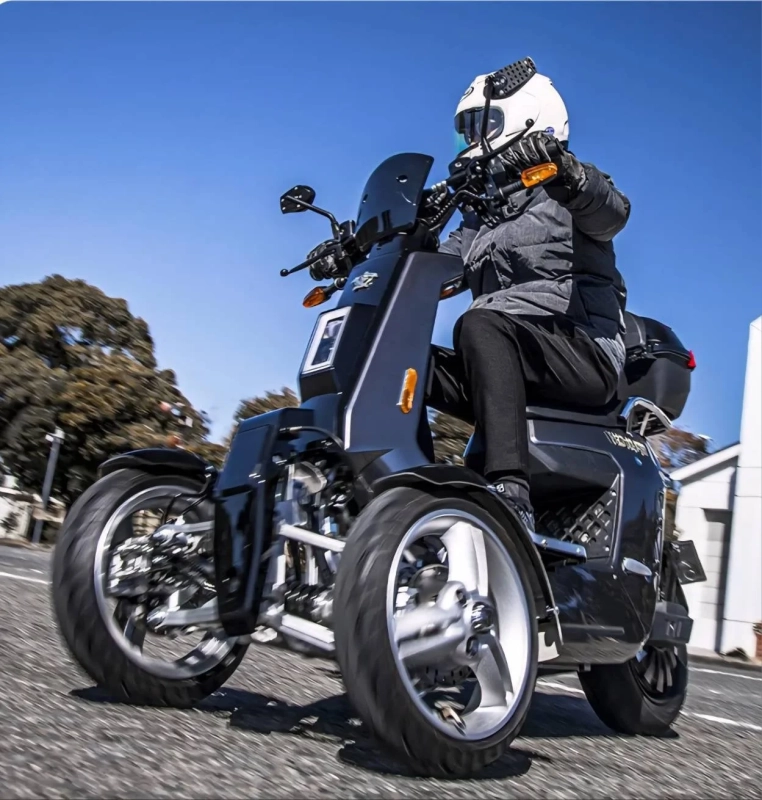 黒い三輪スクーターを運転する人物