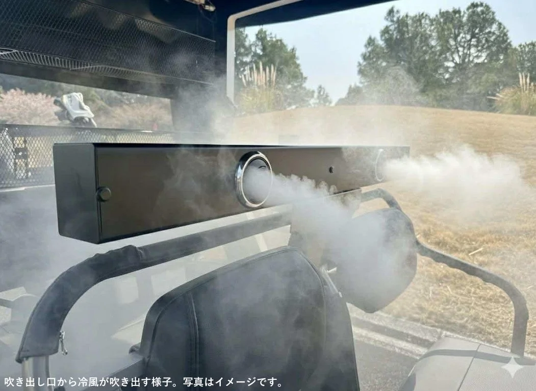 ゴルフカートの車内に設置された黒い冷却装置から、白い冷風またはミストが勢いよく噴き出している様子