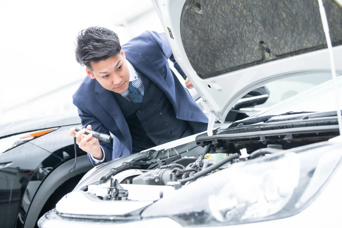 スーツの男性が車のエンジンを点検する様子