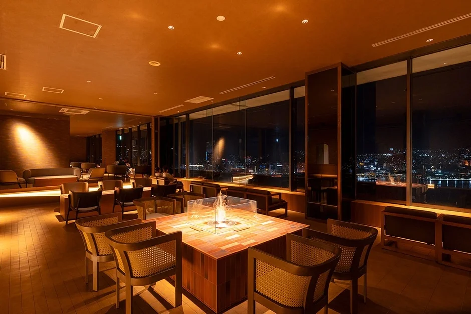 窓の外に広がる美しい夜景を望む、暖炉のある高級感あふれるラウンジ