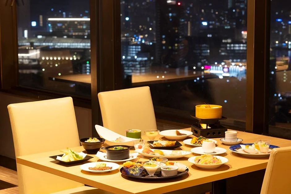 夜景が見える窓際席で、豪華な和食のコース料理が並べられたテーブル