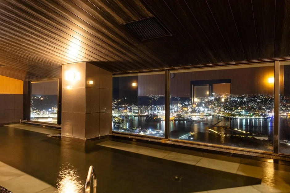 夜の都市と湾を一望できる豪華な屋内プールまたは大浴場