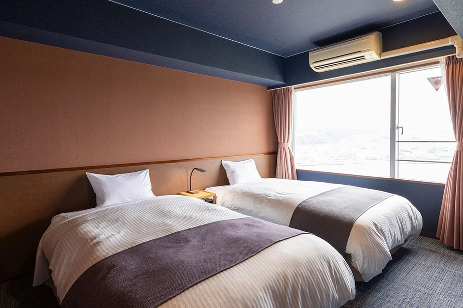 ツインベッドが2台置かれたモダンなデザインのホテル客室