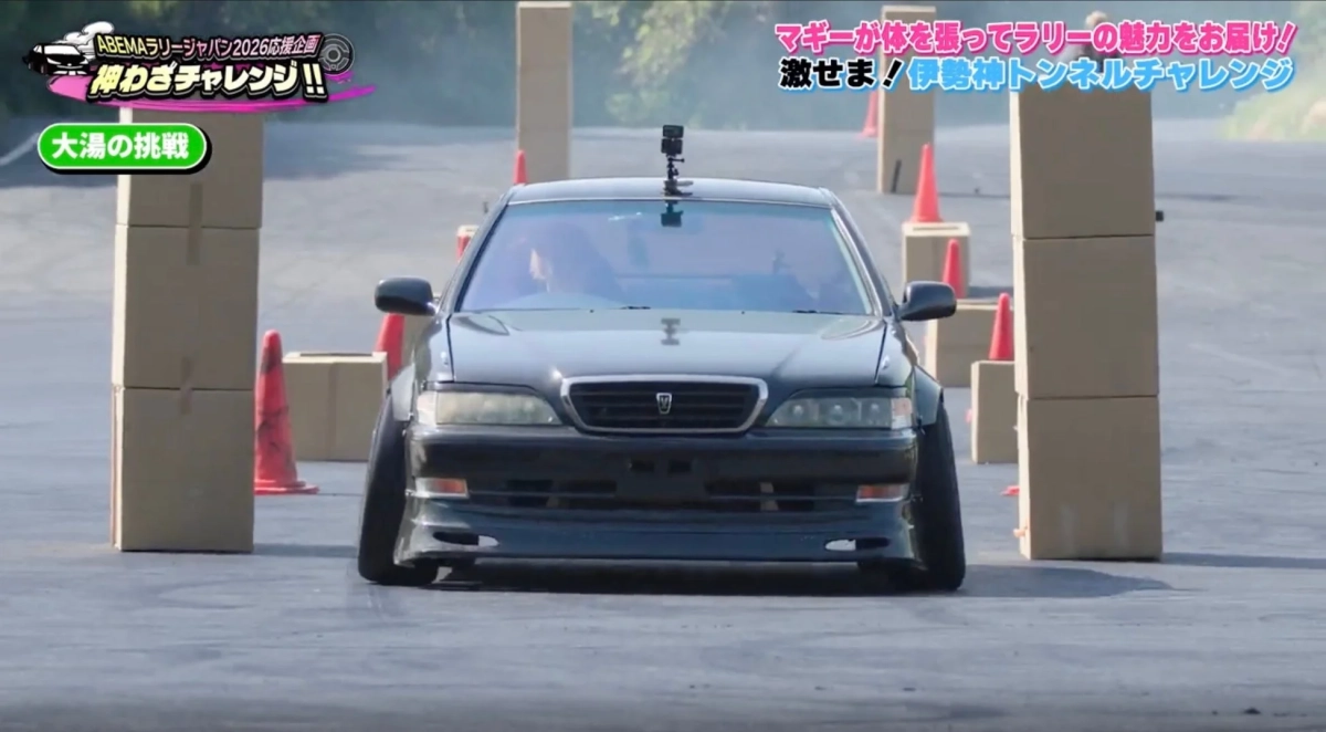 黒い改造車が段ボール箱とパイロンで構成された狭いコースを走行している様子