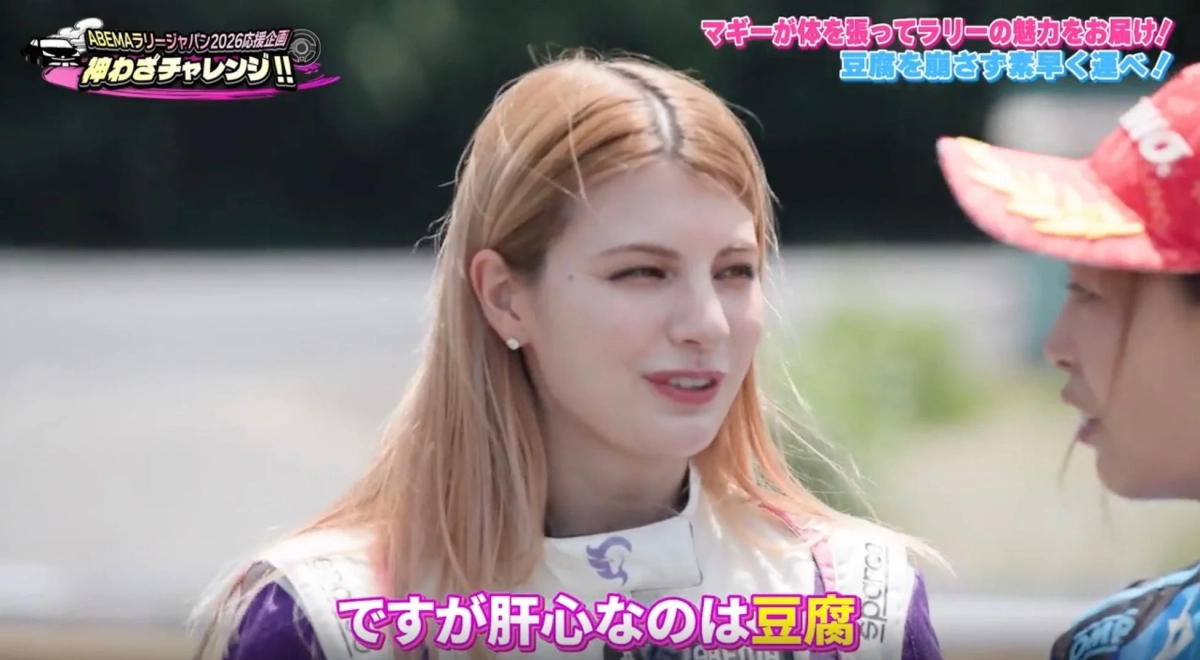 マギーさんがレーススーツ姿で豆腐を崩さずに運ぶというラリーの魅力を伝える挑戦をしています