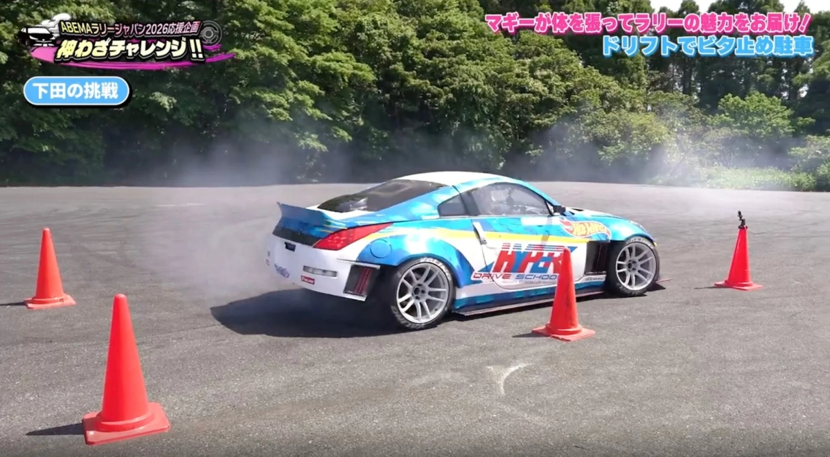 青と白のカスタムスポーツカーが、オレンジのパイロンの間でタイヤスモークを上げながらドリフト走行しています