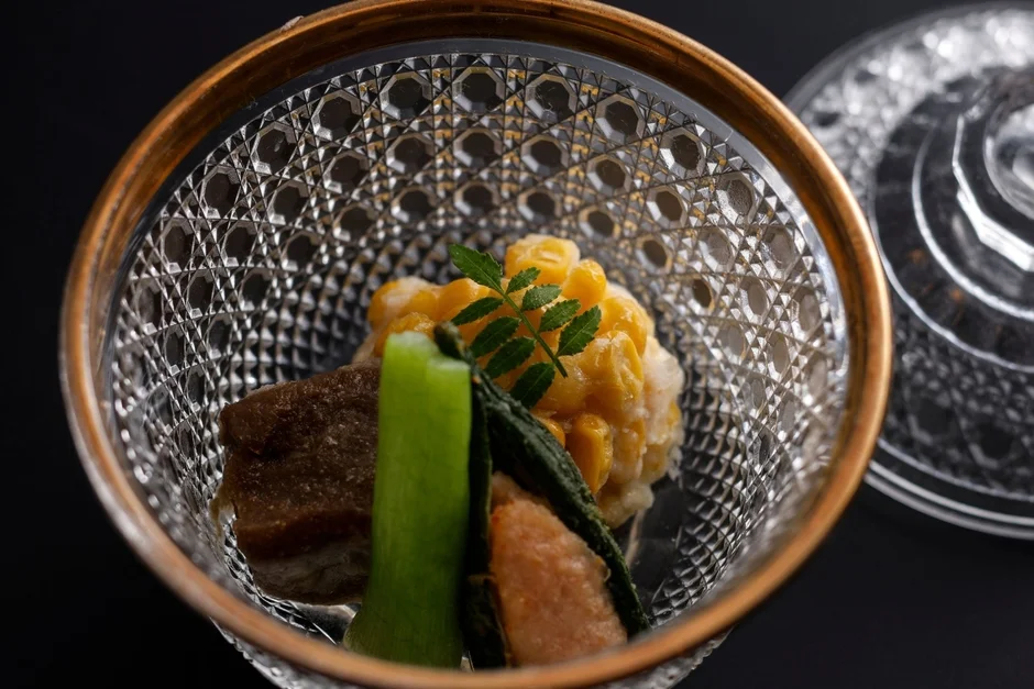 美しいカットガラスの器に盛り付けられた、色とりどりの和食の一品。