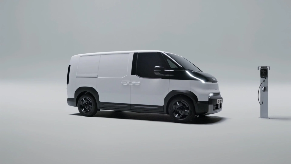 白い電気バンが充電ステーションの隣に駐車している画像です