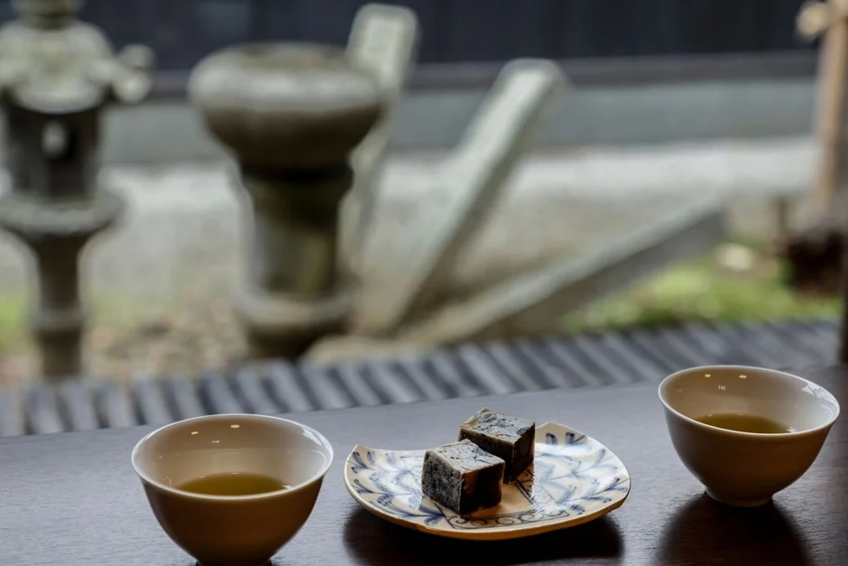 窓辺で日本庭園を眺めながら、お茶と和菓子を楽しんでいる様子。