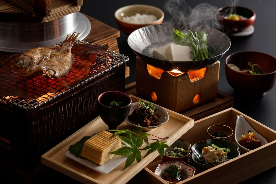 炭火で焼かれた魚、湯気を立てる湯豆腐、釜飯、そして色とりどりの小鉢が並ぶ、豪華で伝統的な和食膳です。