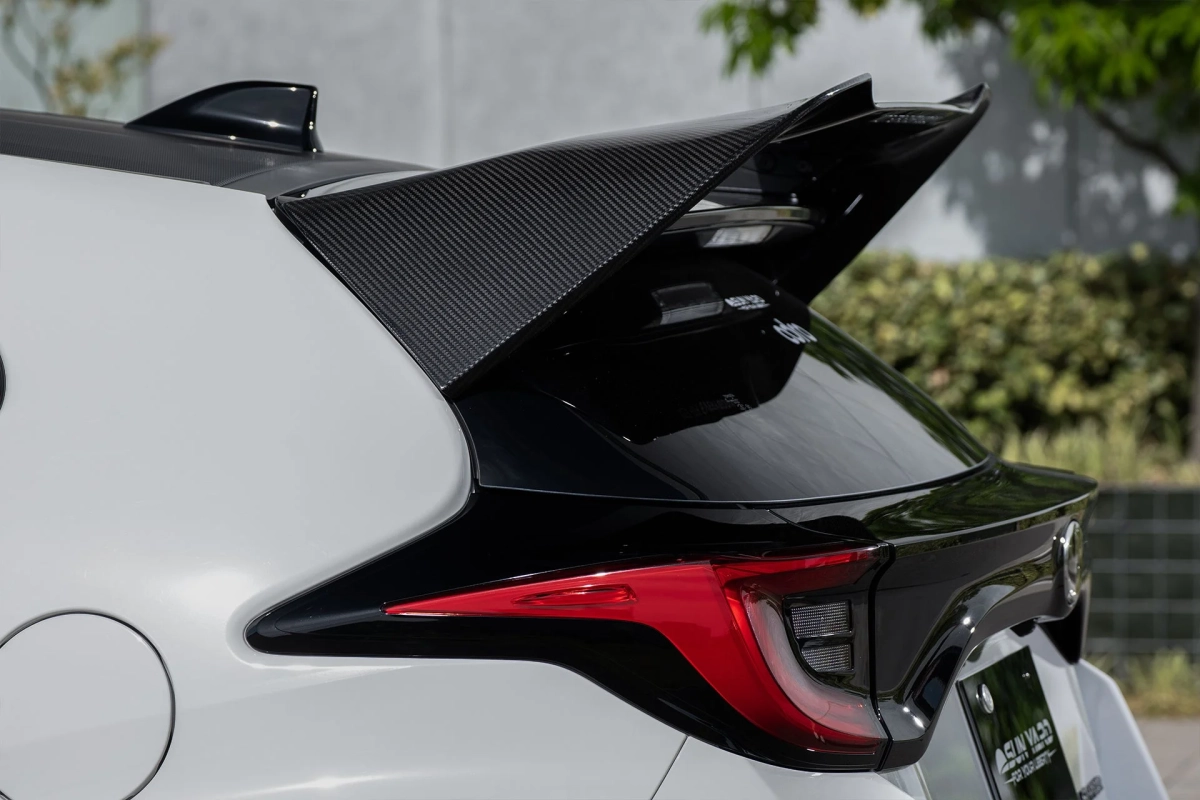 白い車のリア部分をクローズアップした画像で、特徴的なカーボン製大型リアスポイラーとシャープな赤いテールランプが目を引きます。