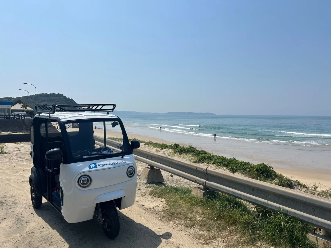 白い電動三輪車が砂浜の脇に駐車された海岸風景