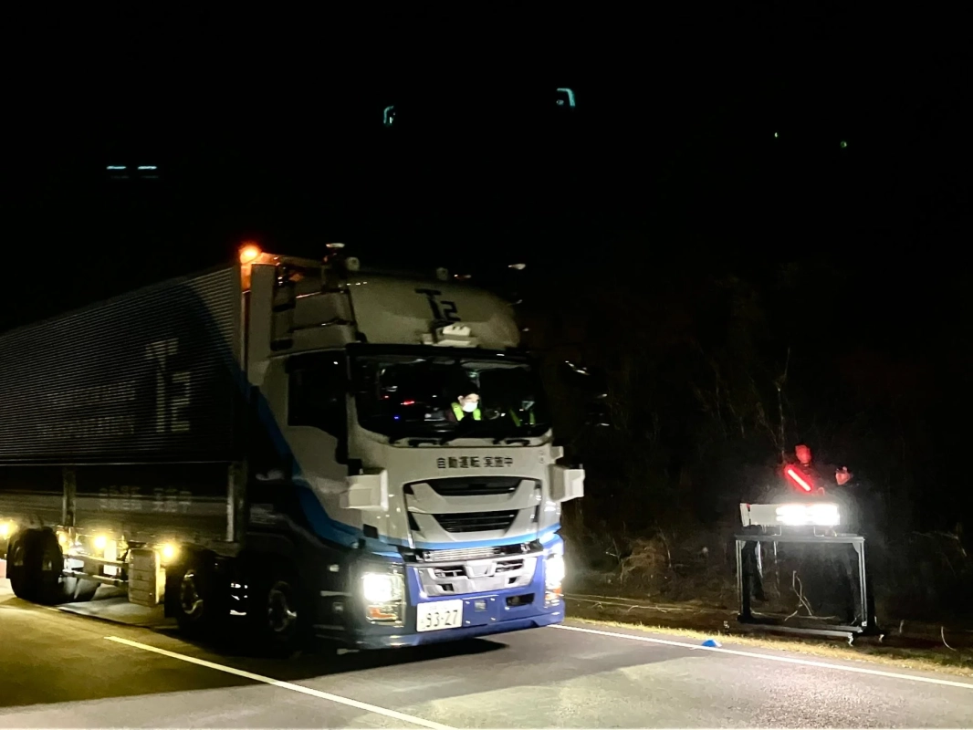 夜間の道路で、ヘッドライトを点灯させた大型トラックが停車している様子