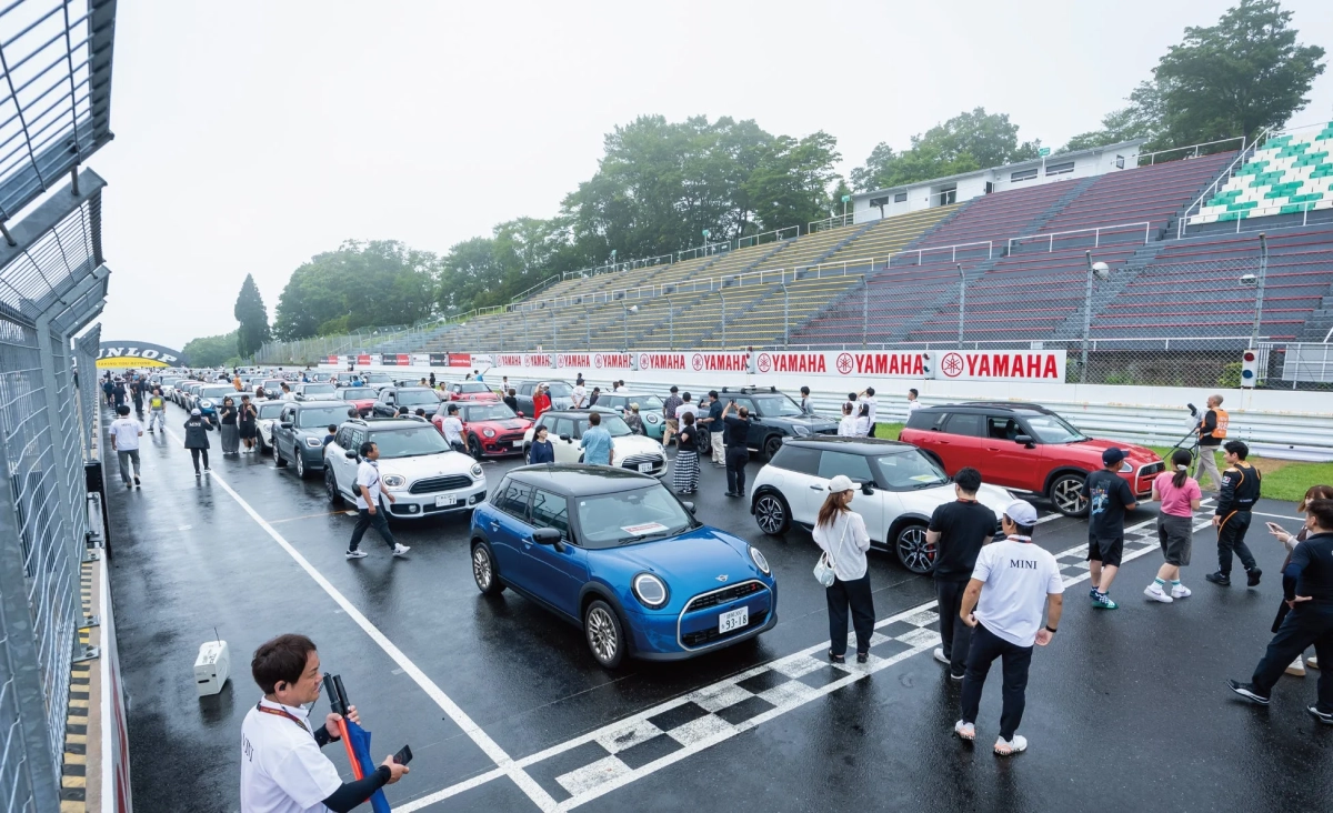 雨上がりのサーキットでパレードランを行うMINIの車列