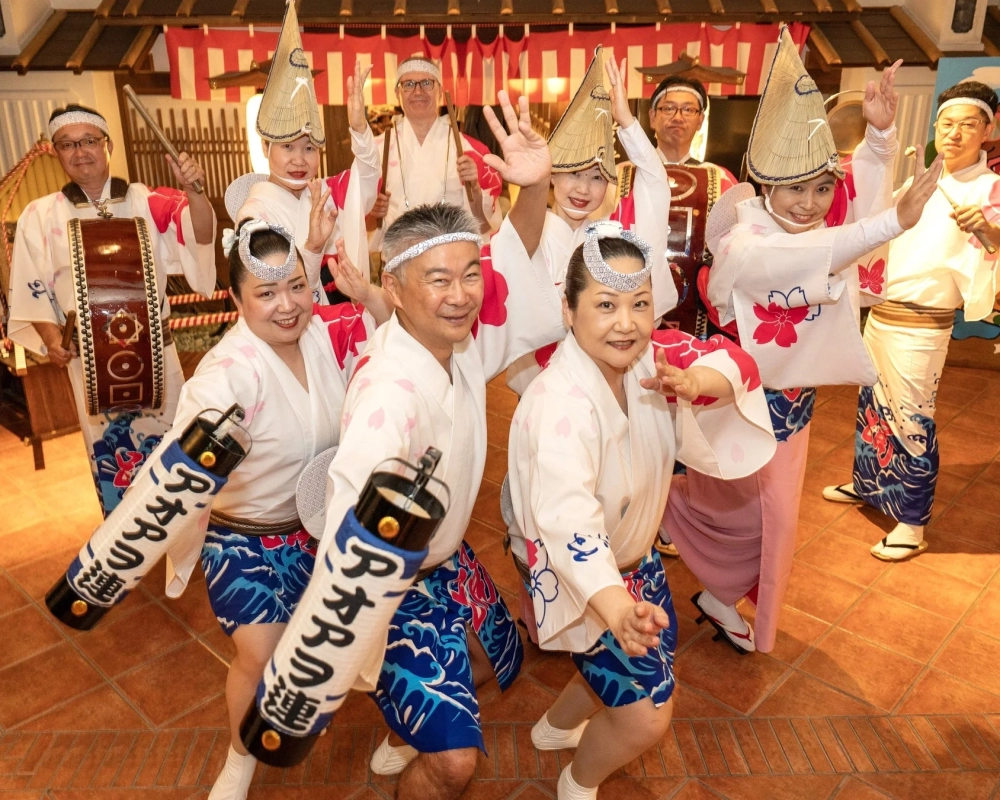 伝統的な衣装を身につけた人々が、阿波踊りのような活気あるパフォーマンスを披露しています