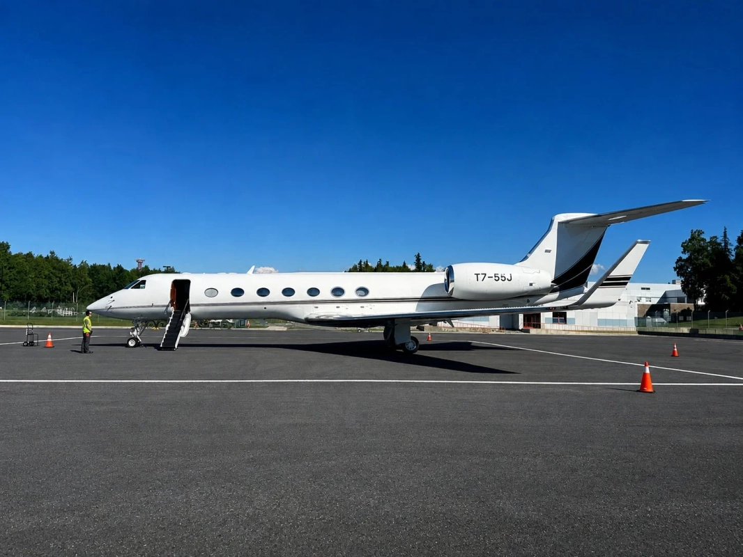 快晴の空の下、滑走路に駐機している白いプライベートジェット機