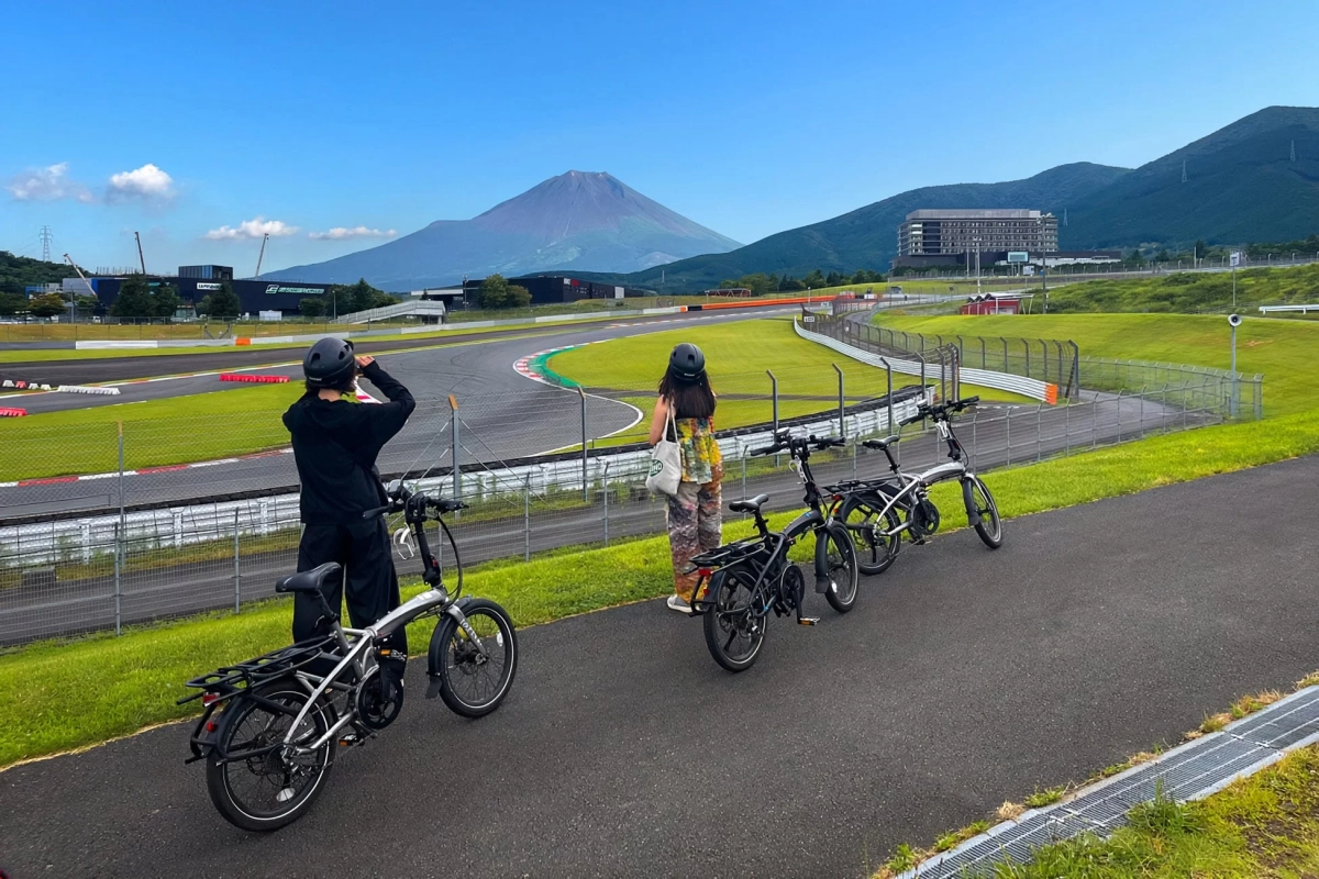 富士山とサーキットを背景に自転車に乗る人々
